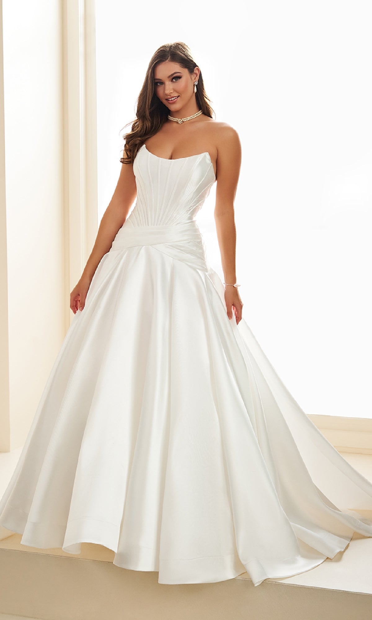 A woman in the Ellie Wilde EW36105 long prom dress, a white strapless mikado ball gown with a corset bodice and dropped waistline.